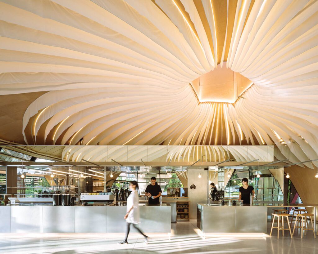 Nemesis Coffee's Vancouver interior with radiating white ceiling fins, metal counters, and cafe staff.