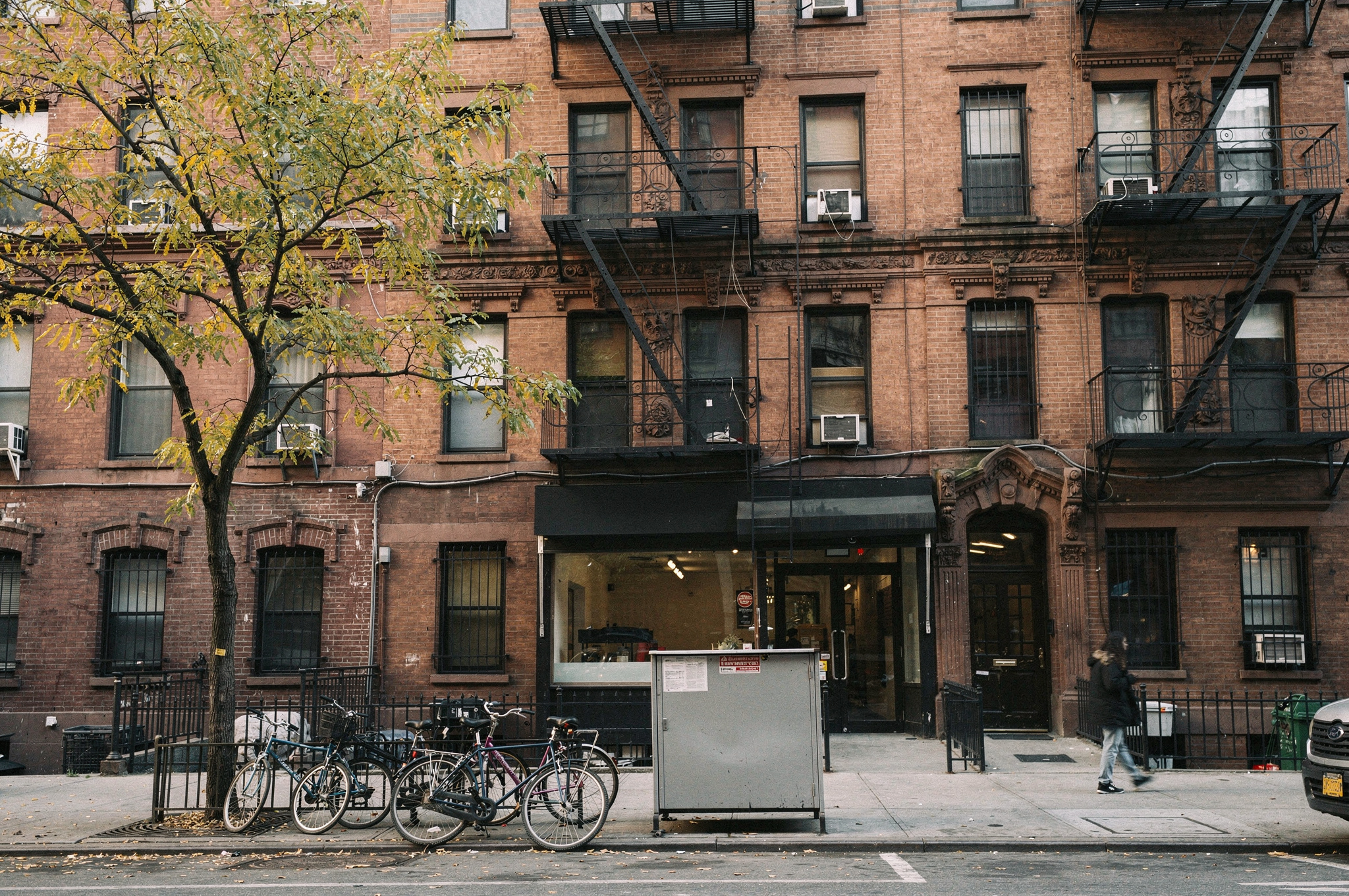 Illustrative image of a six-story brick tenement walk-up with ground-floor retail on the Lower East Side.
