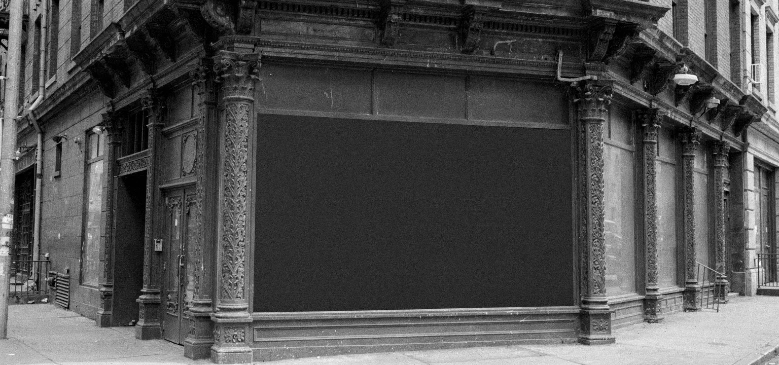The ornate cast-iron facade and empty historic storefront of an older commercial building.
