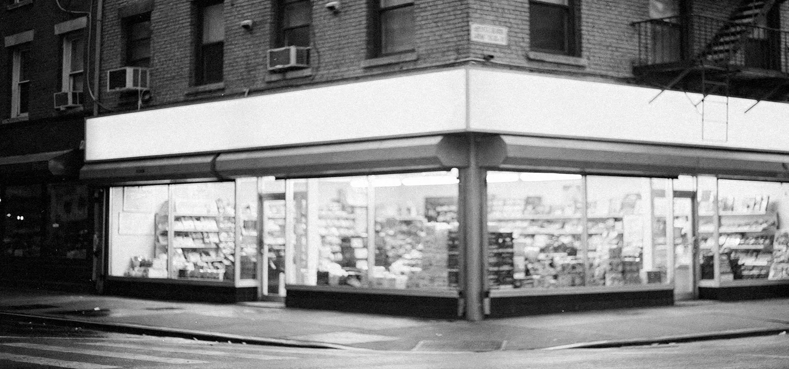 A neighborhood shopping corner with blank storefront awnings, the block where local people actually shop.