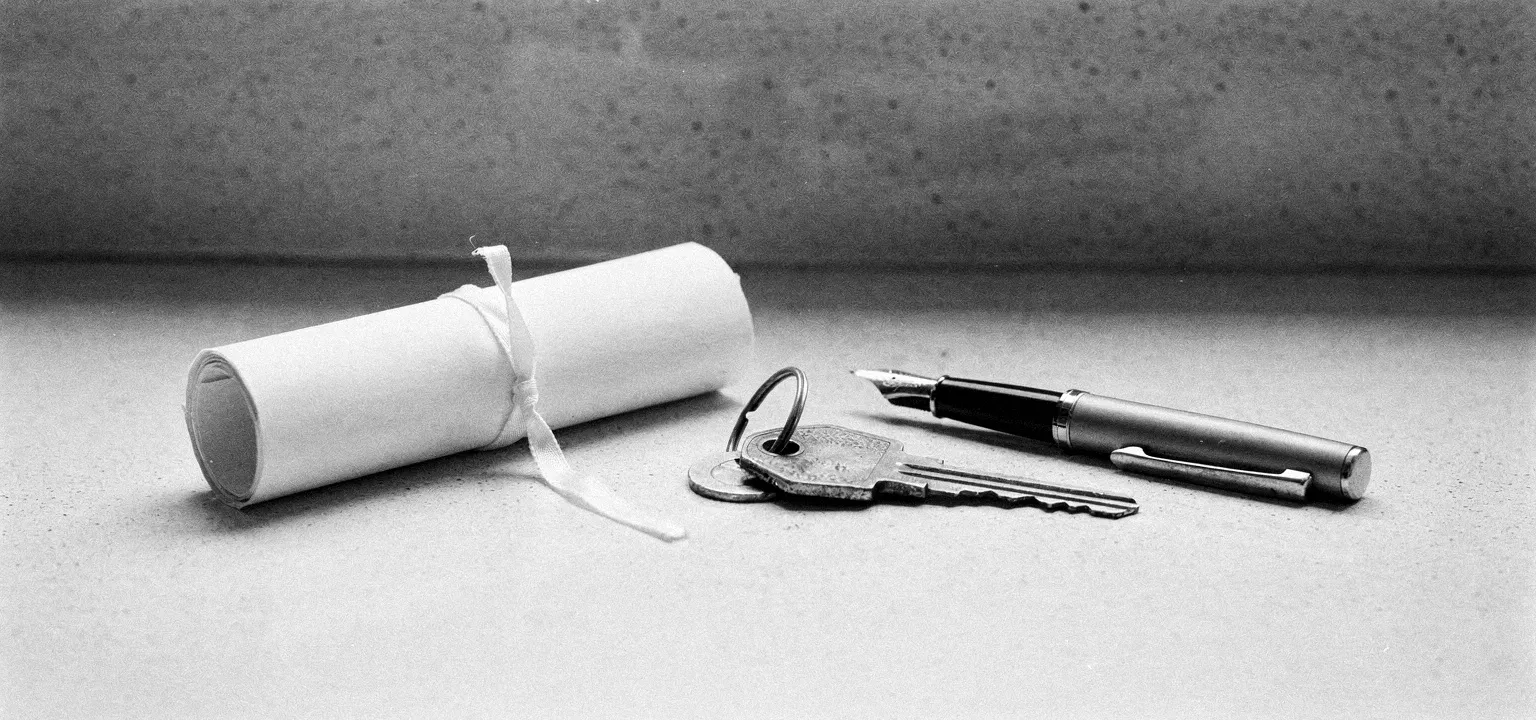 A roll of blank lease documents, a key on a ring, and a pen on a counter — the moment a property is handed over.
