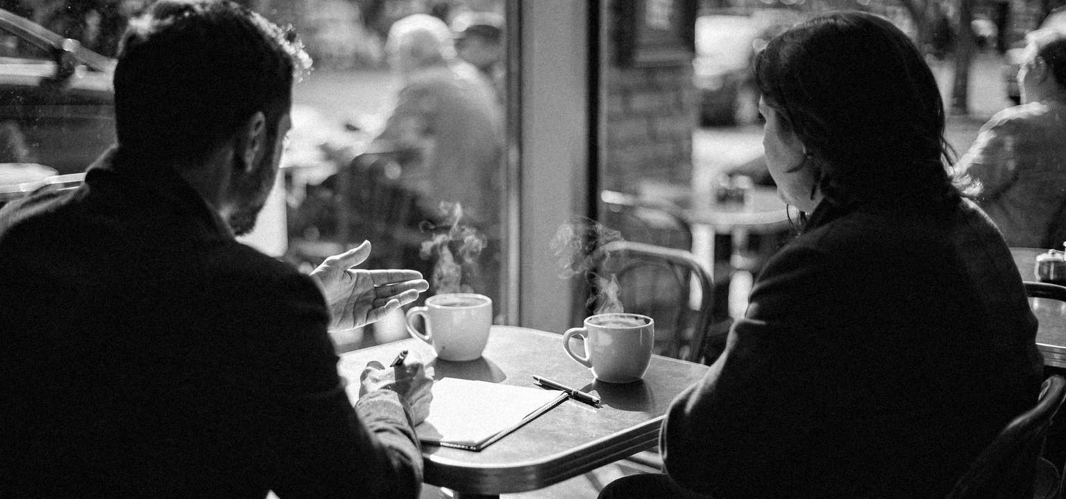 Two people across a table comparing the terms of a retail-deal offer.